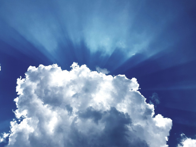 Sonne scheint hinter Wolke am Himmel